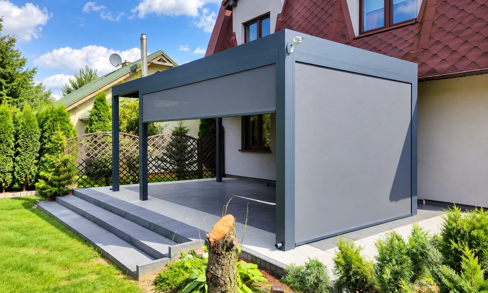 Grafitowa pergola z opuszczoną jasną roletą ZIP przy schodach tarasu