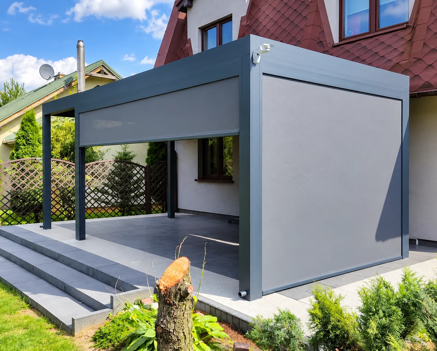 Grafitowa pergola z opuszczoną jasną roletą ZIP przy schodach tarasu